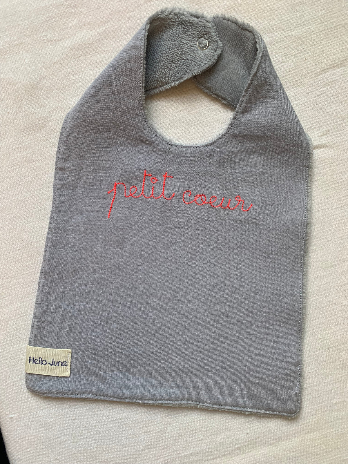 bavoir en lin lavé gris et en douillette de coton grise avec broderie fine "petit coeur" rose fluo fermé par une pression