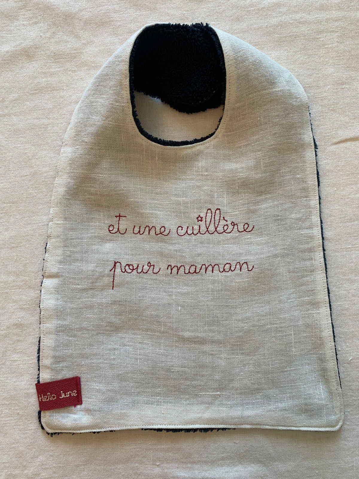 bavoir en lin lavé blanc et en douillette de coton marine avec broderie fine "et une cuillère pour maman" rose fluo fermé par une pression